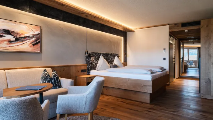Modernes Hotelzimmer mit Holzmöbeln, Doppelbett und gemütlicher Sitzecke